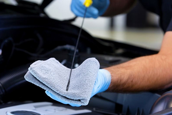 A closeup of a technician with an oil dipstick
