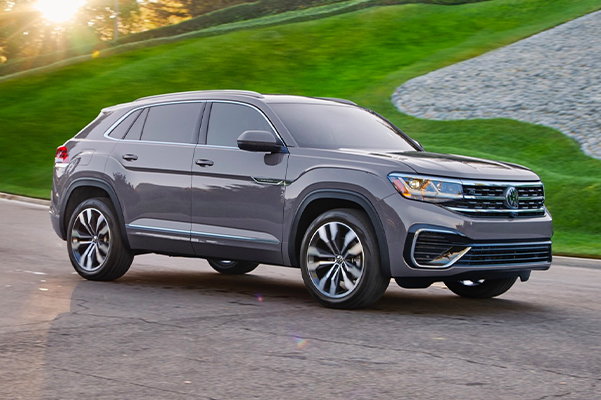 The Atlas Cross Sport drivesalongside a well-manicured lawn filled with gray cobblestones.
